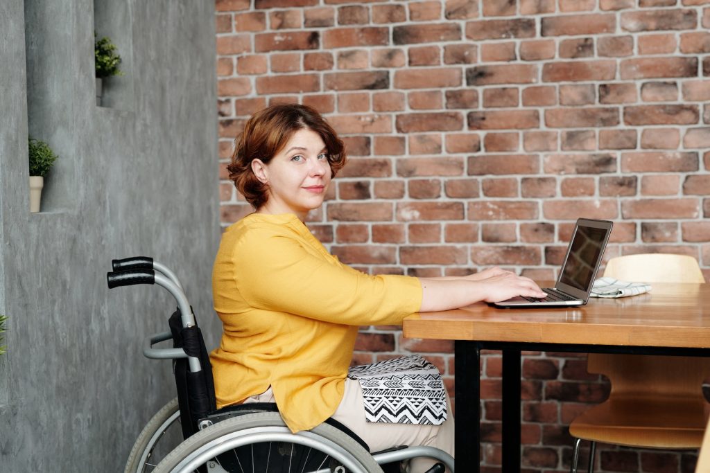 femme en chaise roulante face à son ordinateur de travail